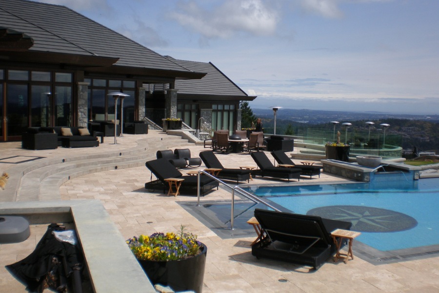 Contemporary Barrie Residence's backyard with a large stone patio, a beautifully tiled pool, outdoor seating, stone features, and a beautiful view.