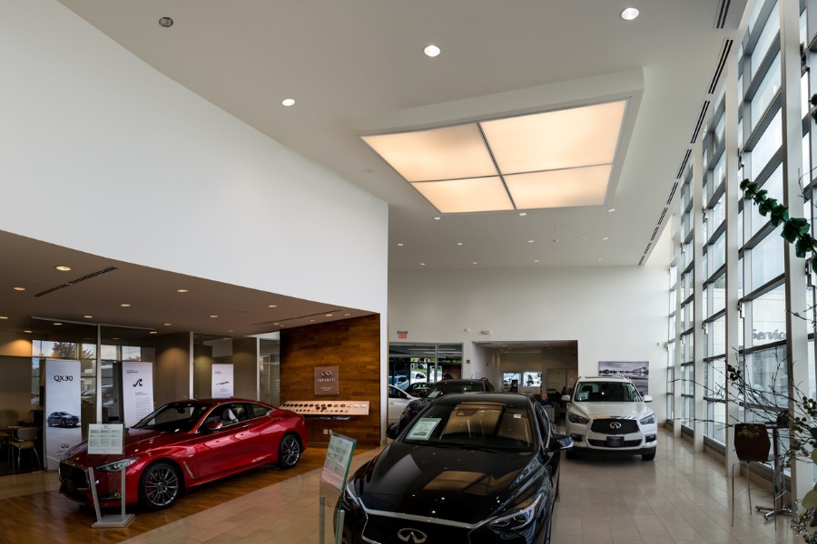 The inside of Campus Infiniti commercial property, designed by Alan Lowe Architecture with large windows, white paint, three Infiniti cars.