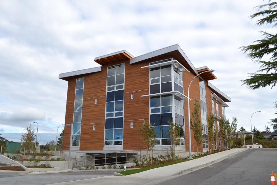 The exterior of King Lasik commercial property, designed by Alan Lowe Architecture with contemporary horizontal wood siding, large windows and angled roof with wood features.