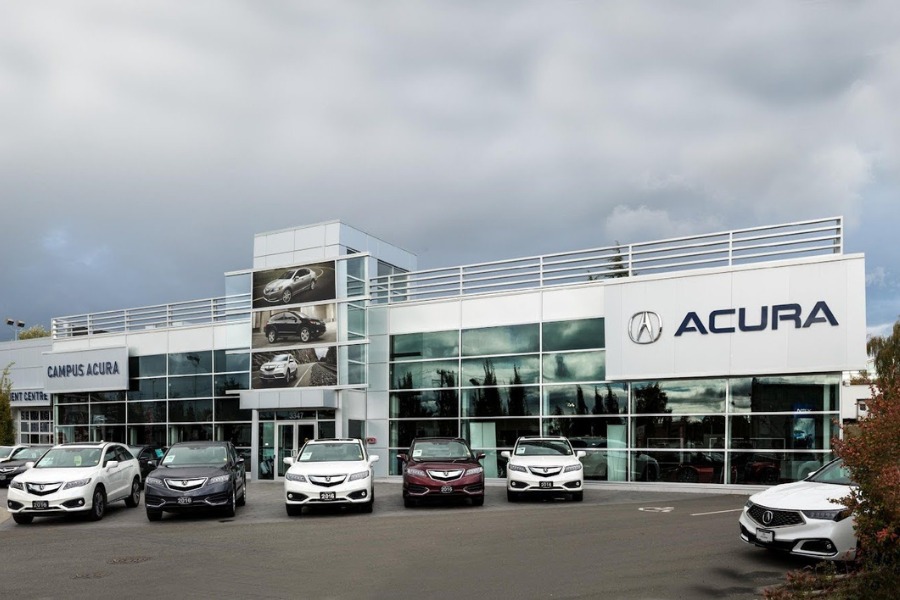 The exterior of Acura commercial property, designed by Alan Lowe Architecture with contemporary grey siding and large signage.
