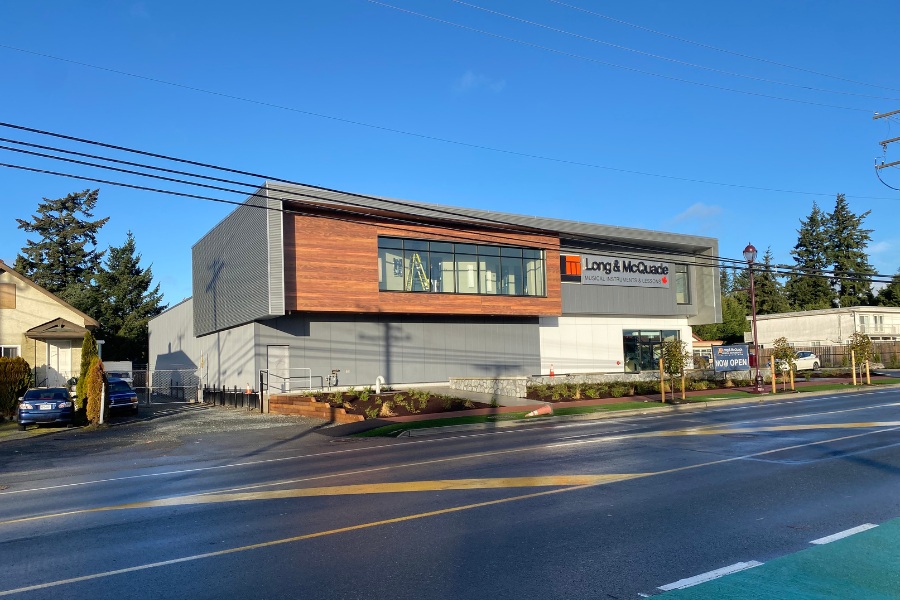 The exterior of Long & McQuade Building, a commercial property, designed by Alan Lowe Architecture with two levels, contemporary design with grey and horizontal wood siding.