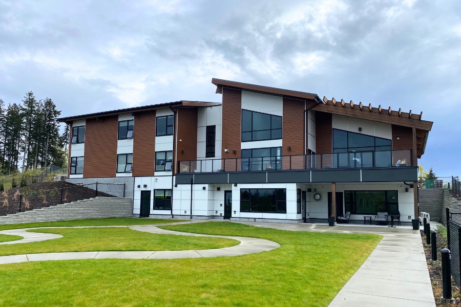 Modern Qwalayu House. designed by Alan Lowe Architecture, with a angled roof, stone and wood features, black trim and expansive windows.
