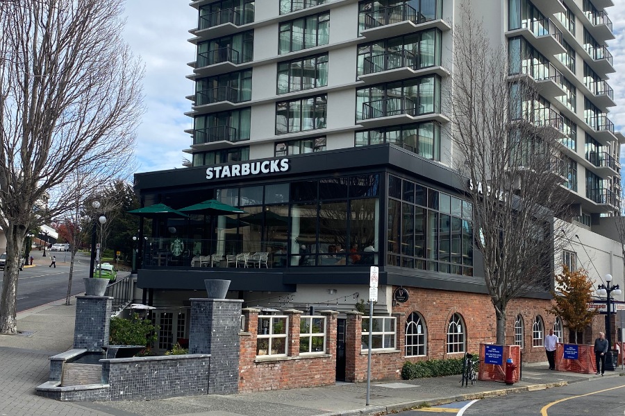 The exterior of a Starbucks building, a commercial property, designed by Alan Lowe Architecture, a two-level building, dark exterior and brick features with floor to ceiling windows on the second floor.